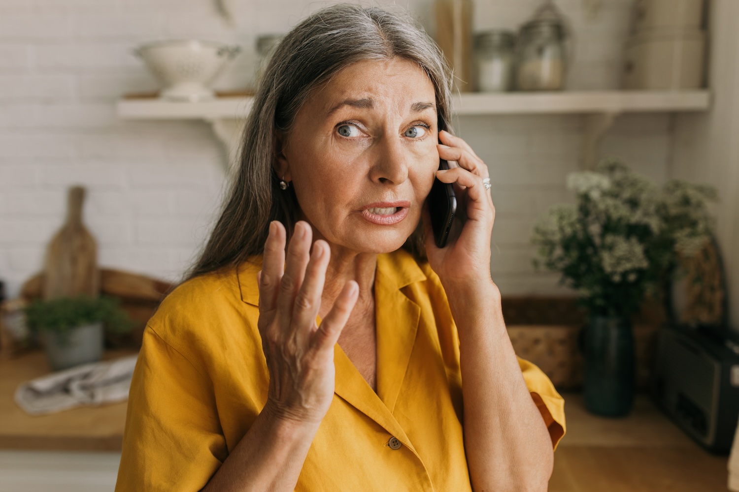 Senior woman talking worriedly on smartphone at home.